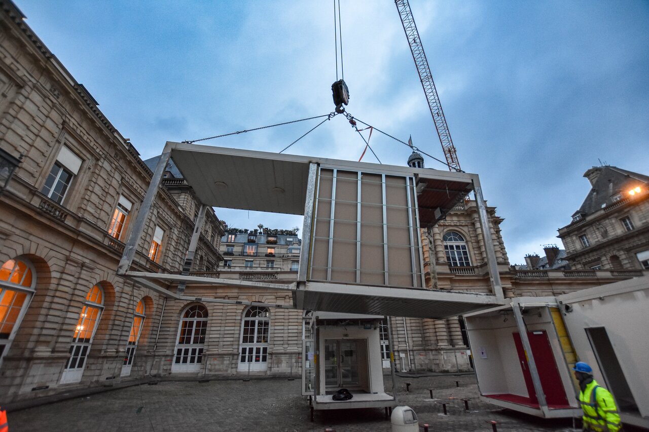Un module suspendu à la grue lors du démontage dans la cour du Sénat.
