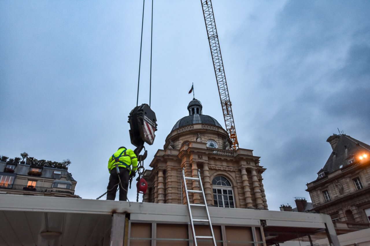 Un intervenant et le crochet de la grue pendant la préparation du démontage modulaire au Sénat.
